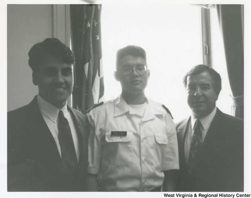 On the right, Representative Nick J. Rahall (D-W.Va.) stands for a photograph with two unidentified men, one of which is in a military uniform.