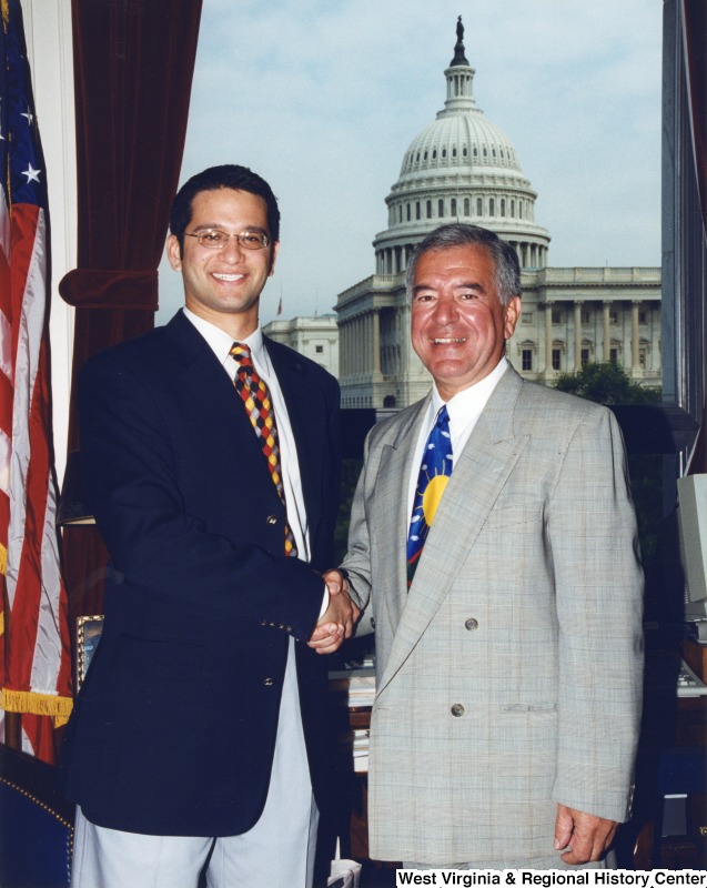 On the right, Representative Nick J. Rahall (D-W.Va.) shakes hands with an unidentified man in his office.