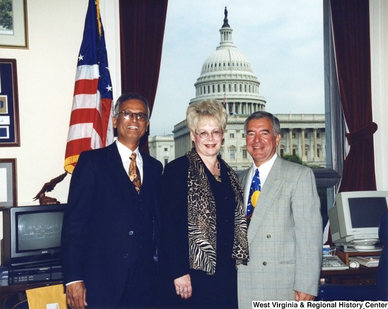 On the right, Representative Nick J. Rahall (D-W.Va.) stands for a photograph in his office with an unidentified man and an unidentified woman.