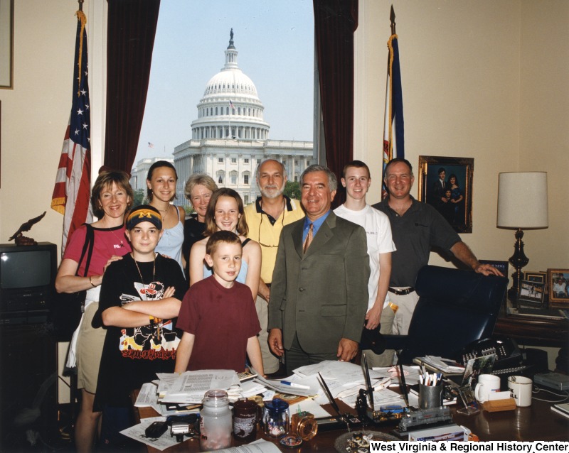 Representative Nick J. Rahall (D-W.Va.) stands among nine unidentified people in his office.