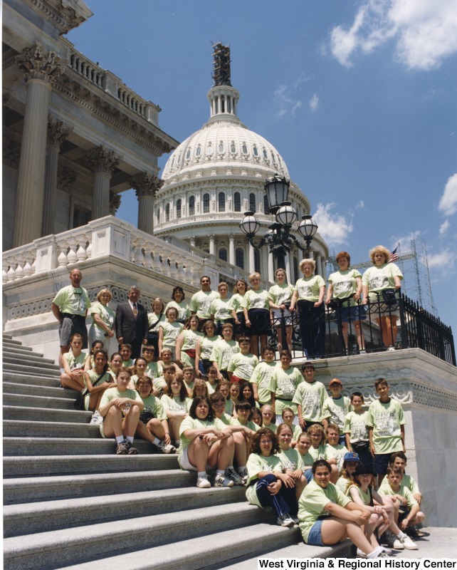 At the top of the stairs, Representative Nick J. Rahall (D-W.Va.) stands for a photograph in front of the Capitol building with students from Bradley Elementary School.